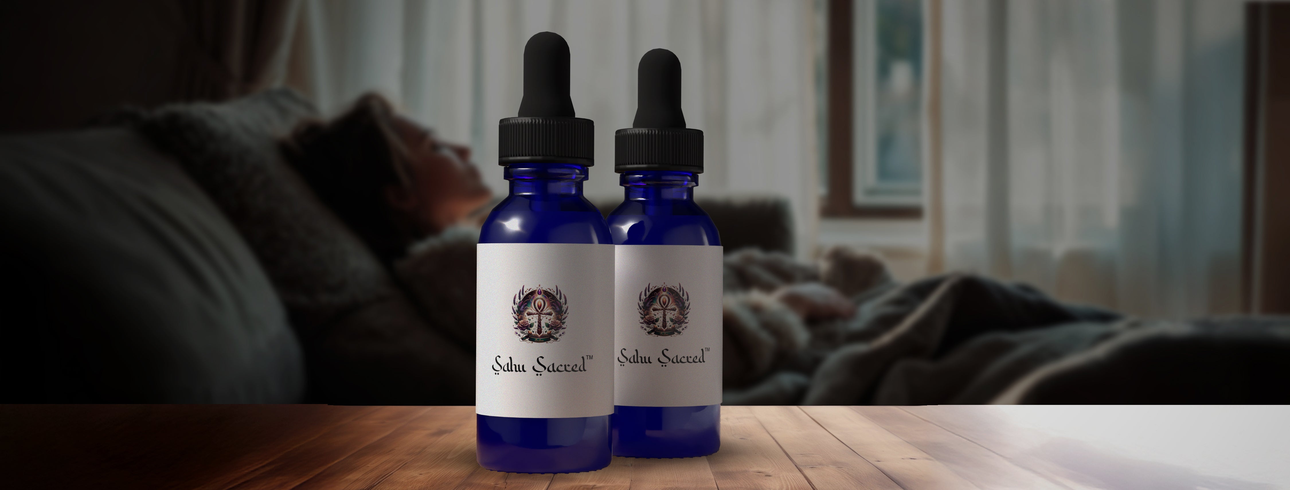 Two blue glass dropper bottles labeled 'Sahu Sacred' placed on a wooden surface, with a blurred background of a woman resting peacefully in bed.