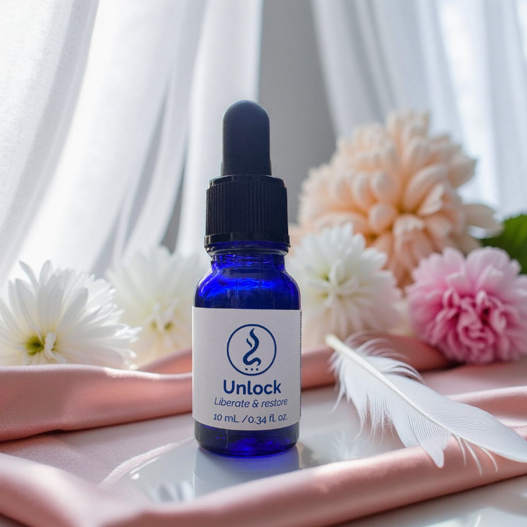 Blue bottle with dropper labeled 'Unlock' on a white surface with flowers and a feather in the background.